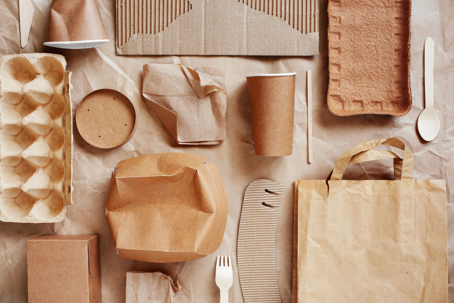 Collection of brown paper products including boxes, bags, and containers on a neutral background.